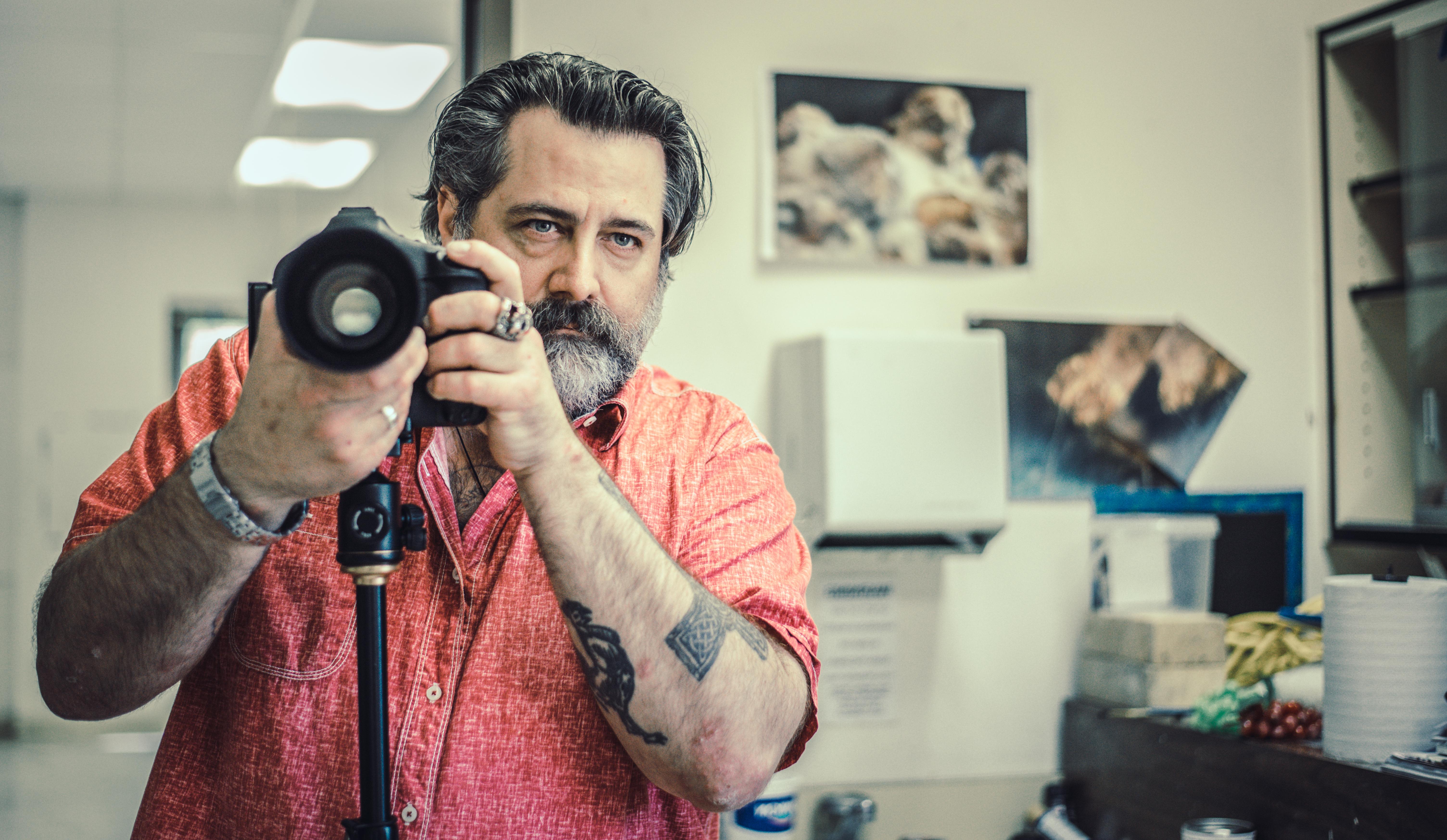 A photography student holds his camera in an art studio